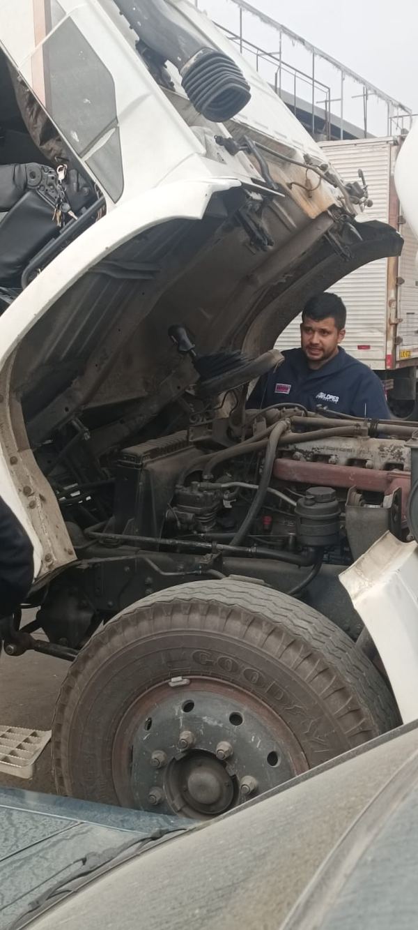 Técnico trabalhando no motor de um caminhão com a cabine basculada
